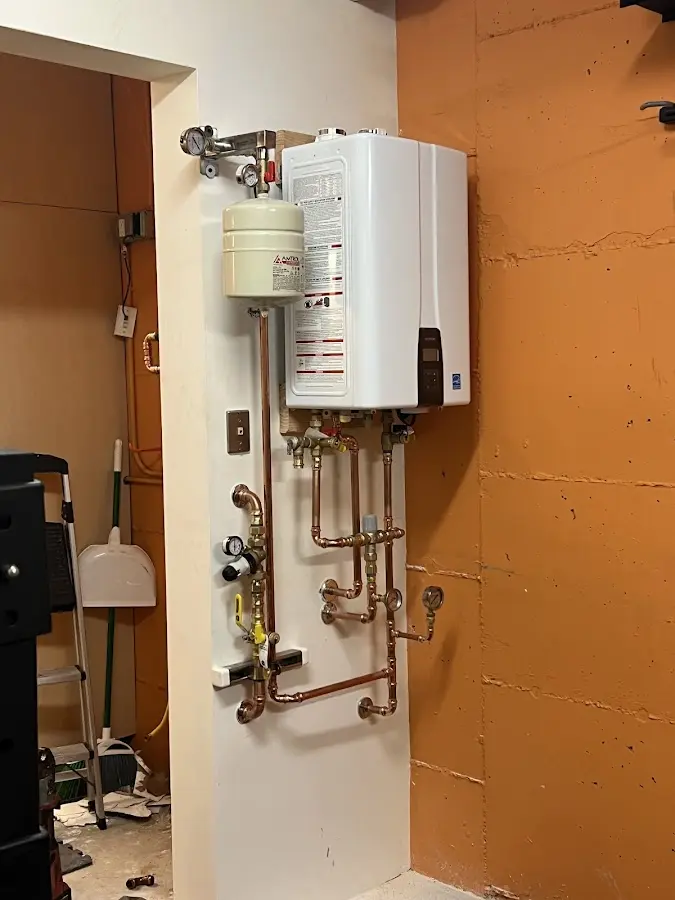 Plumbing technician inspecting water heater connections in Otsego